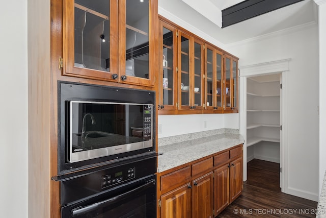 kitchen with crown molding, glass insert cabinets, light stone counters, dark wood finished floors, and black appliances