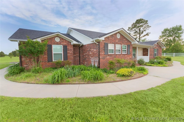 view of front of home featuring a front lawn, fence, and brick siding