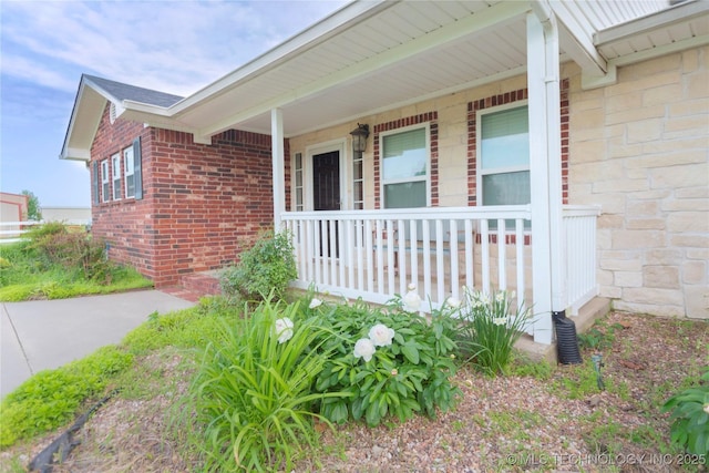 view of exterior entry with covered porch and brick siding