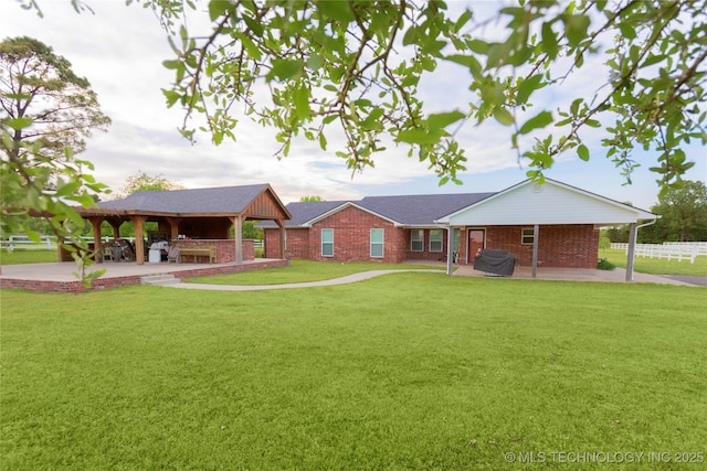 ranch-style home featuring brick siding, fence, a gazebo, a patio, and a front yard