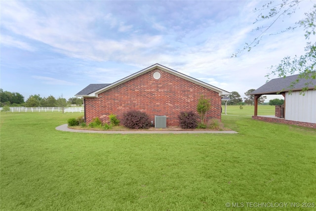 view of home's exterior featuring brick siding, fence, cooling unit, and a lawn
