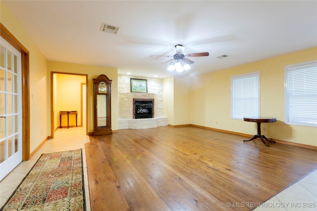 2284 E Roping Rd, Atoka, OK 74525 - unfurnished living room with ceiling fan, a stone fireplace, light tile patterned flooring, and baseboards