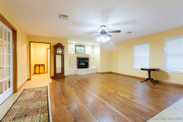 2284 E Roping Rd, Atoka, OK 74525 - unfurnished living room featuring a ceiling fan, a stone fireplace, and light tile patterned flooring