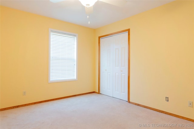 unfurnished bedroom with a closet, baseboards, light carpet, and multiple windows
