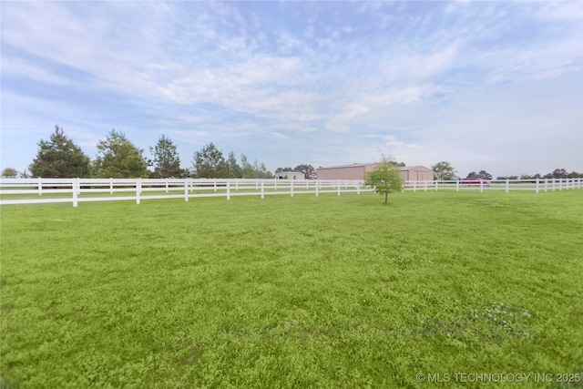 view of yard with fence, a rural view, an outdoor structure, and an exterior structure