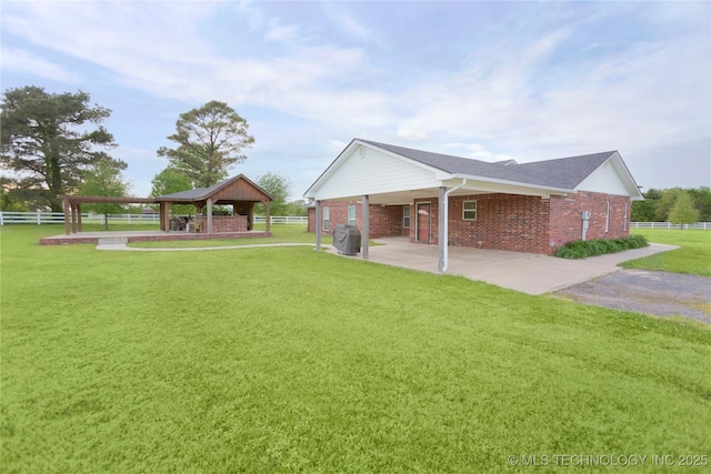 view of side of home with brick siding, a gazebo, fence, and a lawn