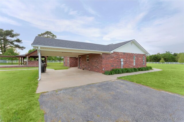 view of front facade featuring brick siding, fence, aphalt driveway, and a front lawn