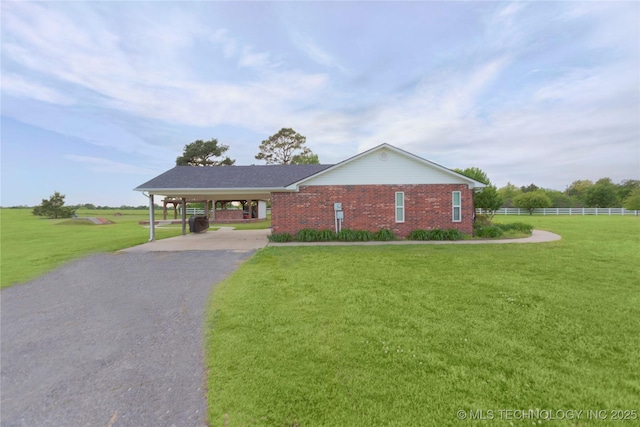 ranch-style home featuring a front lawn, an attached carport, aphalt driveway, brick siding, and fence