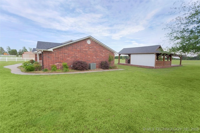 view of home's exterior with brick siding, fence, cooling unit, and a yard