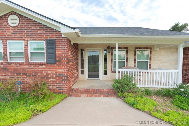2284 E Roping Rd, Atoka, OK 74525 - view of exterior entry with roof with shingles, a porch, and brick siding