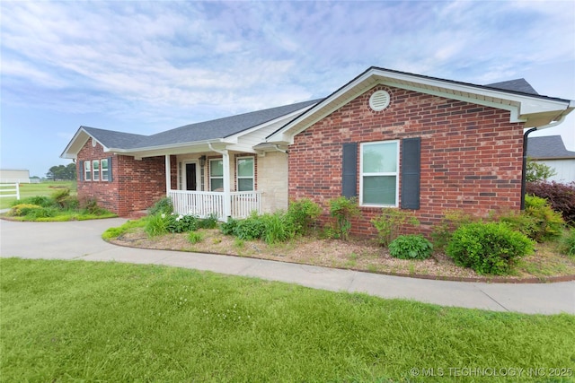 ranch-style home featuring a porch, a front yard, and brick siding