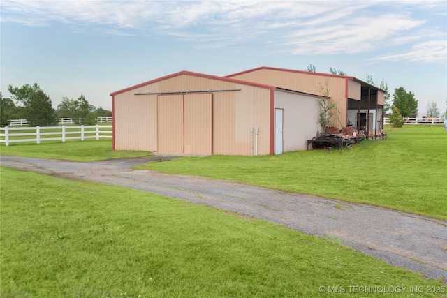 view of pole building with fence, driveway, and a yard