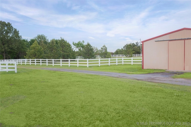 view of yard featuring fence, a pole building, and an outbuilding