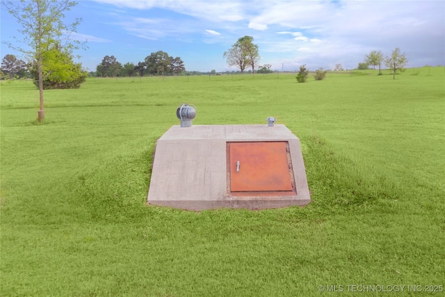 entry to storm shelter with a lawn and a rural view