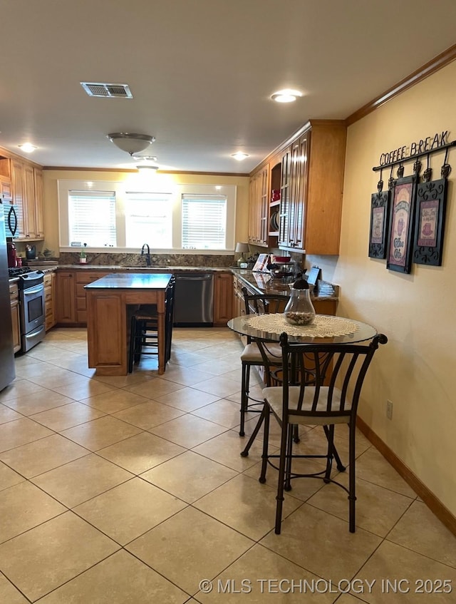 2284 E Roping Rd, Atoka, OK 74525 - kitchen featuring appliances with stainless steel finishes, dark countertops, light tile patterned flooring, a kitchen island, and open shelves