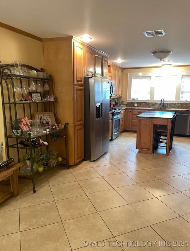 2284 E Roping Rd, Atoka, OK 74525 - kitchen featuring stainless steel appliances, a sink, ornamental molding, light tile patterned floors, and dark countertops
