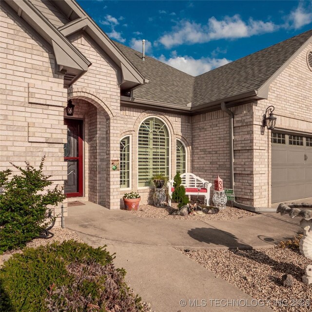 1904 Sandpiper St, Mcalester, OK 74501 - doorway to property featuring a garage, brick siding, and roof with shingles