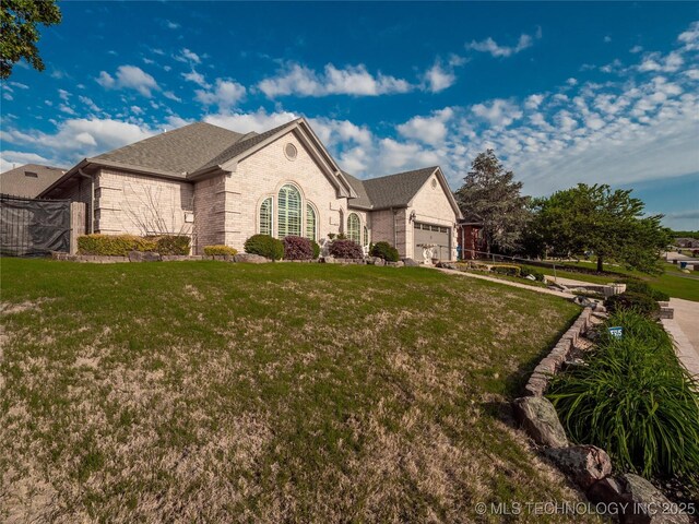 1904 Sandpiper St, Mcalester, OK 74501 - view of front of property featuring a front yard, an attached garage, a shingled roof, and brick siding