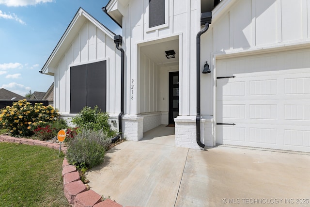 9218 N 141st E Ave, Owasso, OK 74055 - view of exterior entry with board and batten siding, concrete driveway, and a garage