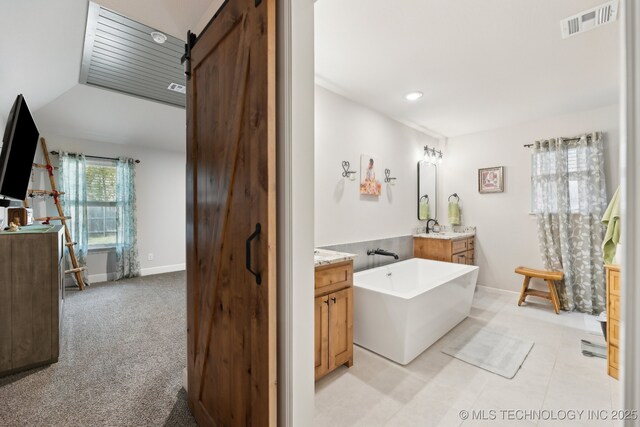 9218 N 141st E Ave, Owasso, OK 74055 - bathroom featuring two vanities, visible vents, a freestanding bath, vaulted ceiling, and baseboards