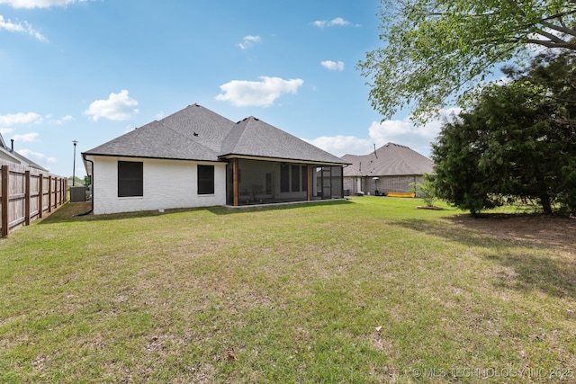 9218 N 141st E Ave, Owasso, OK 74055 - rear view of house featuring fence, roof with shingles, a lawn, and a sunroom