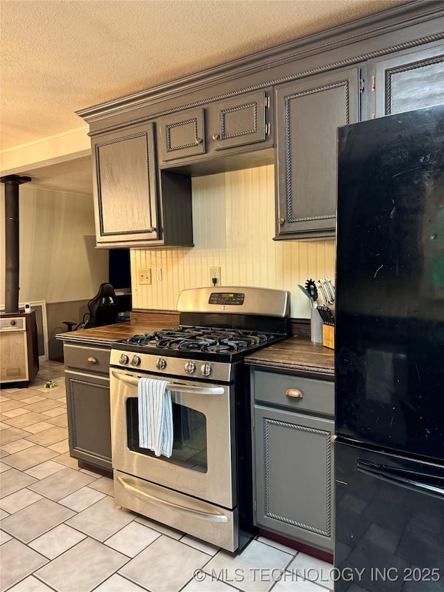 9585 Celia Berryhill Rd, Okmulgee, OK 74447 - kitchen with gas range, freestanding refrigerator, light tile patterned floors, a textured ceiling, and gray cabinets