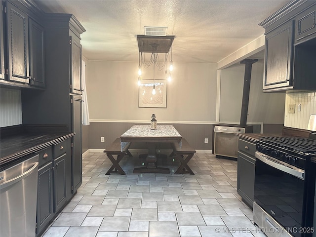 9585 Celia Berryhill Rd, Okmulgee, OK 74447 - kitchen featuring stainless steel appliances, a wainscoted wall, a textured ceiling, and pendant lighting