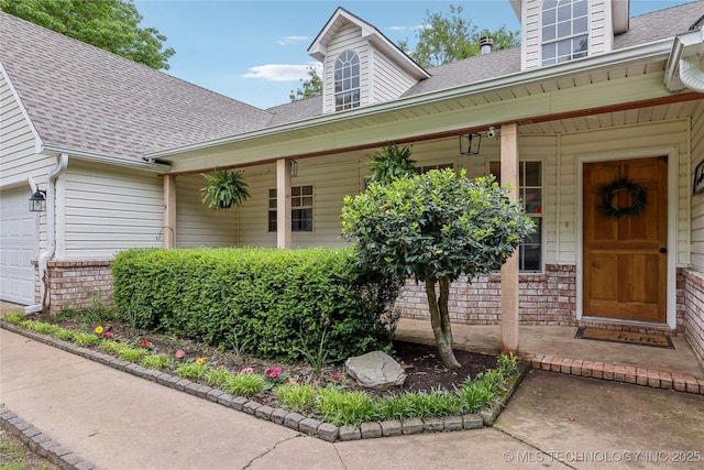 doorway to property with a porch and a shingled roof