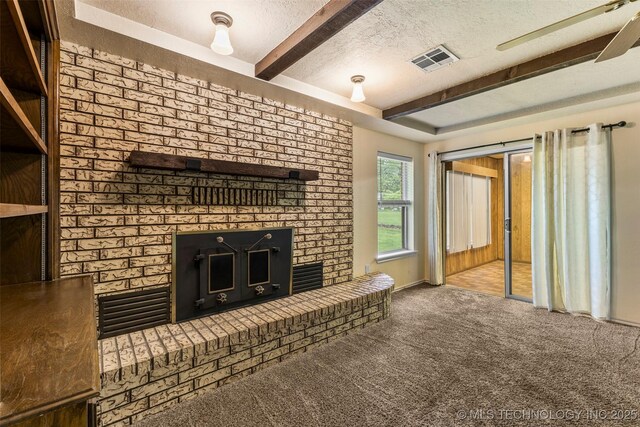 unfurnished living room with beam ceiling, a fireplace, visible vents, carpet, and a textured ceiling