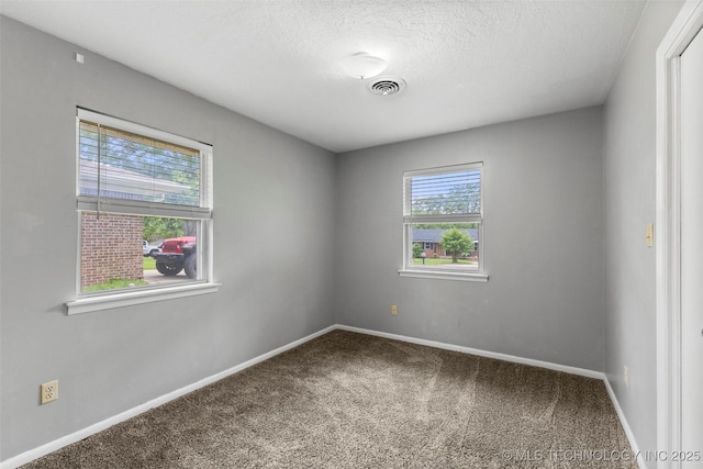 carpeted spare room with baseboards, visible vents, and a textured ceiling