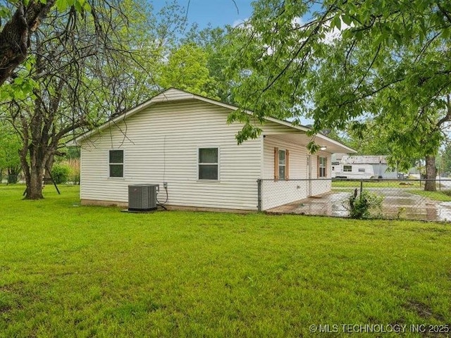 view of property exterior with fence, a yard, and central air condition unit
