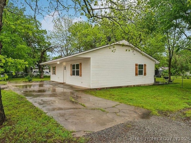 view of property exterior with a lawn, driveway, and fence