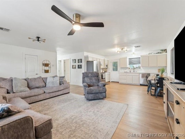 living room with visible vents, a ceiling fan, and light wood finished floors