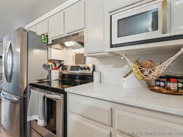 kitchen with under cabinet range hood, tasteful backsplash, white cabinetry, light stone counters, and appliances with stainless steel finishes