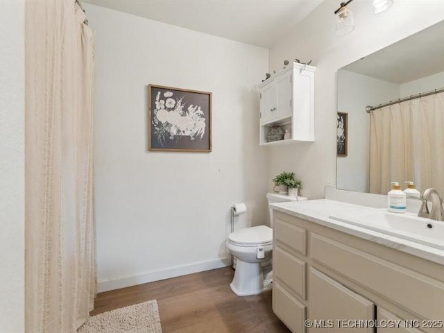 bathroom with baseboards, wood finished floors, toilet, and vanity