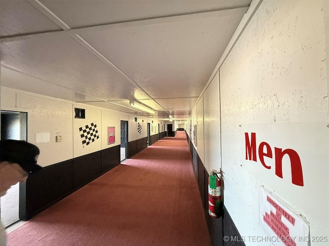 hall featuring a textured wall and carpet