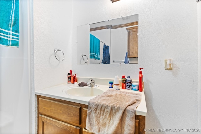 full bathroom featuring a textured wall and vanity