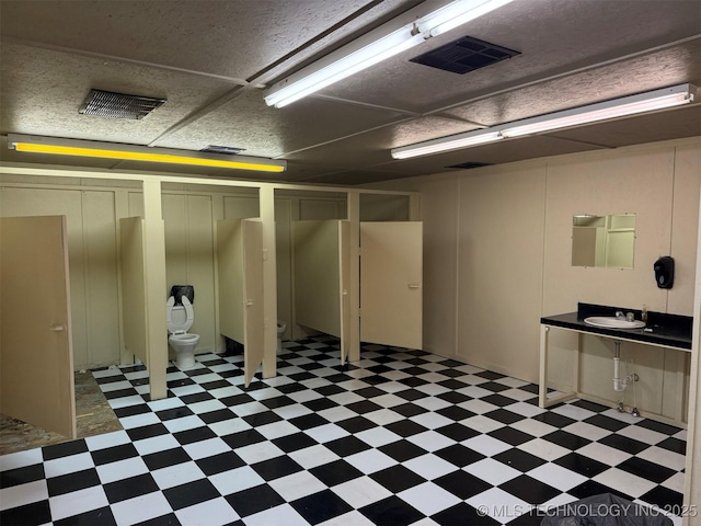 finished basement with tile patterned floors, visible vents, and a sink