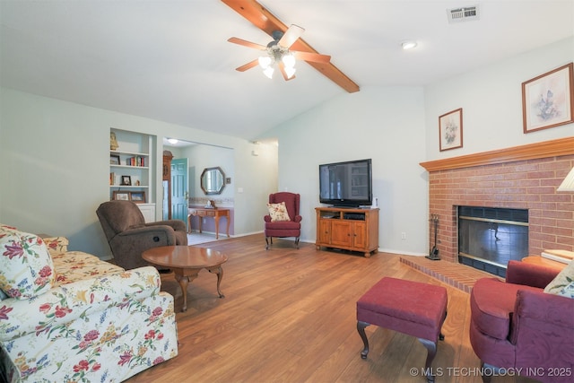 living room featuring visible vents, lofted ceiling with beams, light wood-type flooring, a brick fireplace, and a ceiling fan