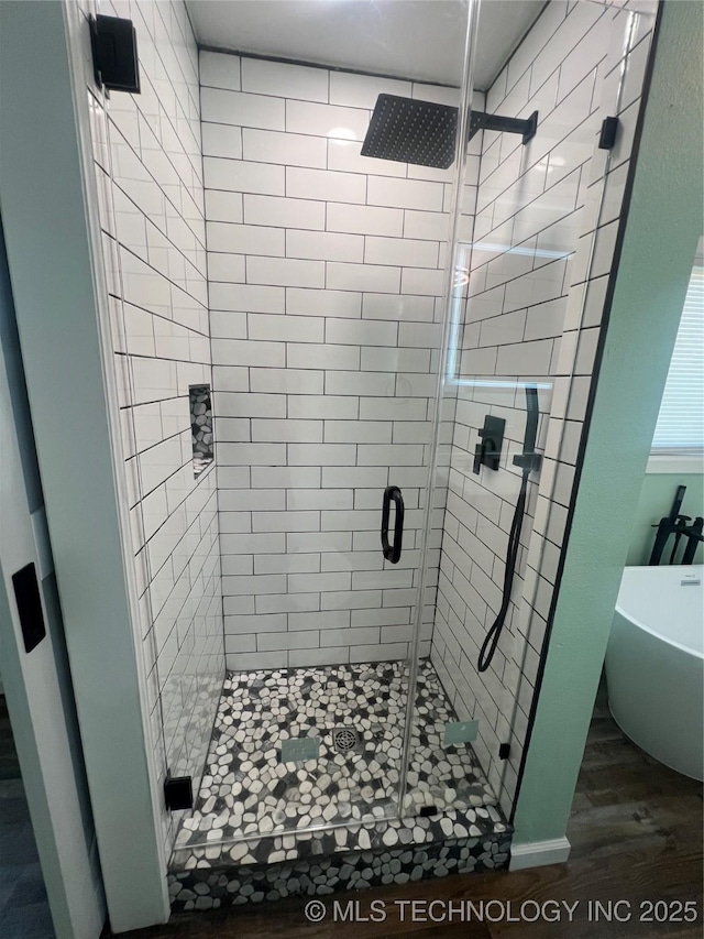 bathroom with wood finished floors, a freestanding bath, and a stall shower