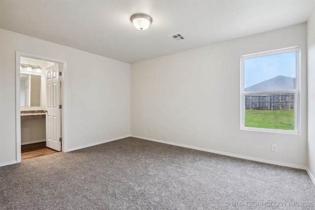 unfurnished bedroom featuring carpet, visible vents, ensuite bathroom, and baseboards