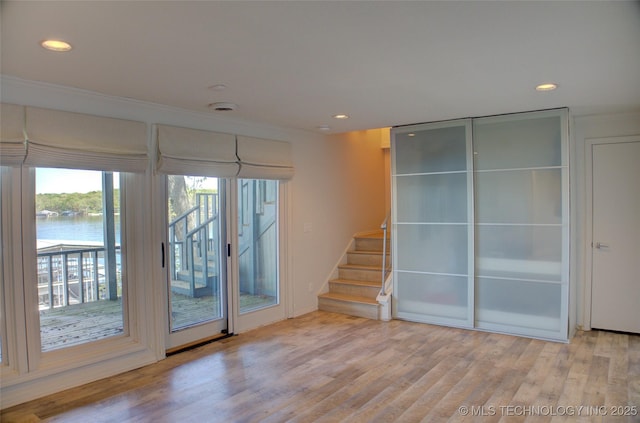 entryway with recessed lighting, a water view, stairway, and wood finished floors