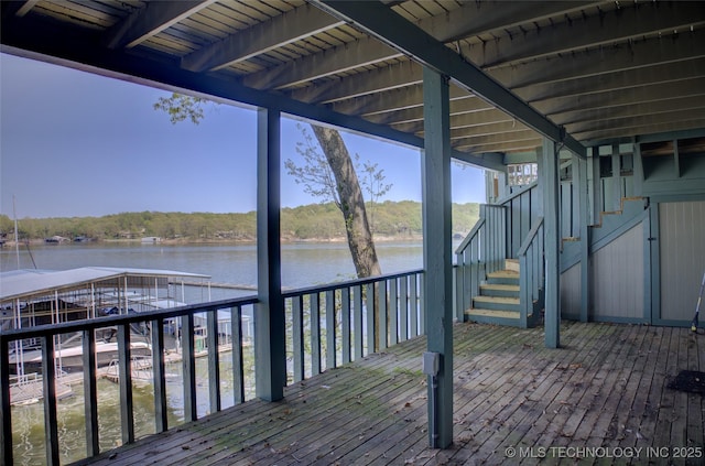 wooden deck with stairs, a water view, a dock, and boat lift
