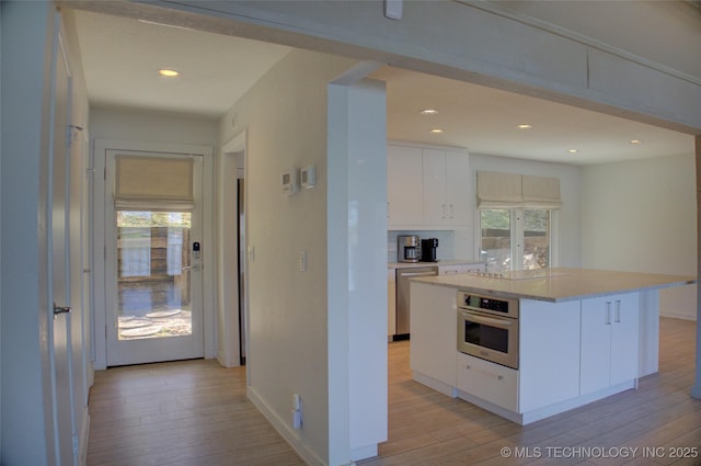 kitchen with light wood-style flooring, white cabinets, appliances with stainless steel finishes, and light countertops