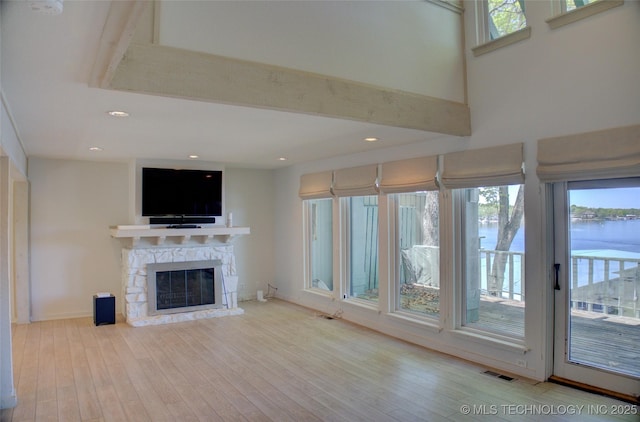 unfurnished living room with visible vents, wood finished floors, a fireplace, and plenty of natural light