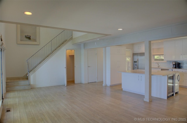 unfurnished living room with visible vents, recessed lighting, light wood-style flooring, and stairs