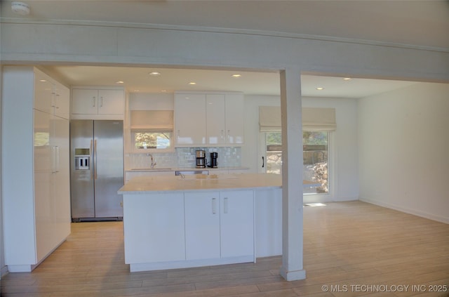 kitchen with a sink, modern cabinets, light wood-style floors, white cabinetry, and stainless steel fridge with ice dispenser
