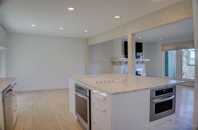 kitchen with light wood-type flooring, white cabinetry, stainless steel appliances, and recessed lighting