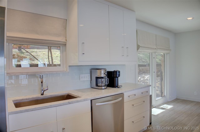 kitchen featuring a healthy amount of sunlight, tasteful backsplash, stainless steel dishwasher, and a sink