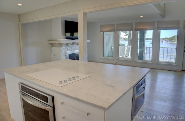kitchen featuring light wood finished floors, white cabinets, and stainless steel oven